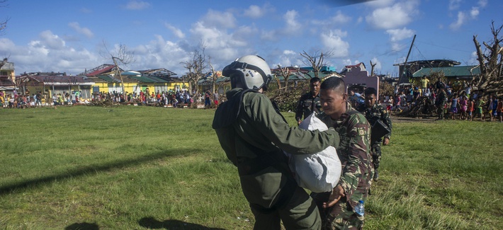 A Naval Aircrewman delivers relief supplies to a Filipino Army soldier A Naval Aircrewman delivers relief supplies to a Filipino Army soldier