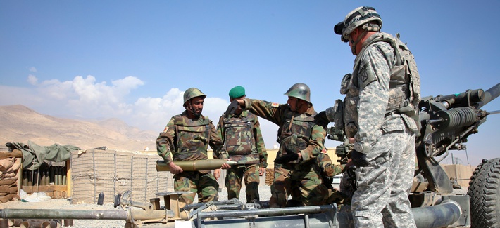 An ANA soldier carries a 105 mm round while training on an M119 Howitzer An ANA soldier carries a 105 mm round while training on an M119 Howitzer