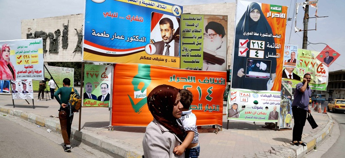 An Iraqi woman walks past a series of billboards advertising election candidates in Iraq An Iraqi woman walks past a series of billboards advertising election candidates in Iraq