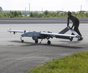 An avionics maintenance technician pushes an RQ7-B drone back to the taxiway after landing An avionics maintenance technician pushes an RQ7-B drone back to the taxiway after landing