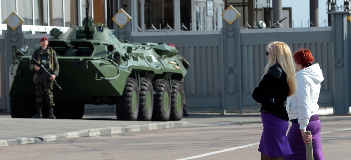 Two Ukrainian women walk past an armored personnel carrier in Kiev, Ukraine. Two Ukrainian women walk past an armored personnel carrier in Kiev, Ukraine.