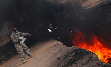 A sergeant tosses unusable uniform items into a burn pit at a base in Balad, Iraq, on March 10, 2008. A sergeant tosses unusable uniform items into a burn pit at a base in Balad, Iraq, on March 10, 2008.