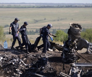 Ukrainian emergency workers on Monday carry a victim's body in a plastic bag at the crash site of Malaysia Airlines Flight 17. Ukrainian emergency workers on Monday carry a victim's body in a plastic bag at the crash site of Malaysia Airlines Flight 17.