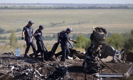Ukrainian emergency workers on Monday carry a victim's body in a plastic bag at the crash site of Malaysia Airlines Flight 17. Ukrainian emergency workers on Monday carry a victim's body in a plastic bag at the crash site of Malaysia Airlines Flight 17.