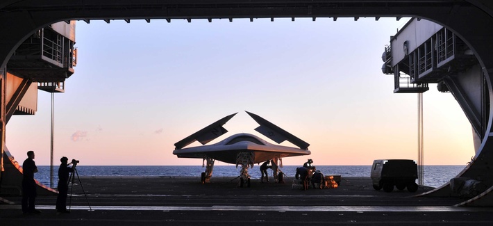 An X-47B Unmanned Combat Air System demonstrator is loaded on an aircraft elevator aboard the USS George H.W. Bush, on May 14, 2014.