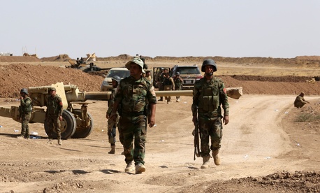 Kurdish peshmerga forces stand by their vehicles after they take control of a village from ISIS fighters, on October 1, 2014. 