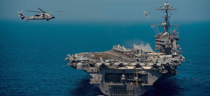 An MH-60S Knight Hawk helicopter attached to the Chargers of Helicopter Sea Combat Squadron (HSC) 14 performs plane guard operations near the aircraft carrier USS John C. Stennis.