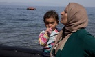 A dinghy full of migrants approaches the coast of the Greek island of Lesbos after crossing from Turkey to Greece as a Syrian woman who just arrive holds her child,Thursday, Sept. 10, 2015.
