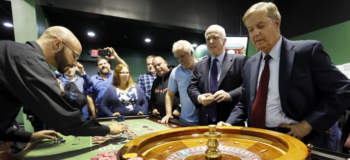 Republican presidential candidate Sen. Lindsey Graham, R-S.C., right, watches as he and Sen. John McCain, R-Ariz., play the roulette wheel at a charitable gaming poker room during a campaign stop at the Manchester Bingo Center and Poker Room Oct. 9, 2015.