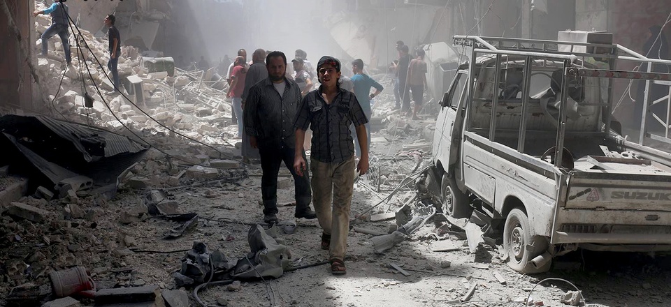 This July. 26, 2016 file photo, provided by the Syrian anti-government activist group Aleppo Media Center (AMC), shows Syrian citizens inspect damaged buildings after airstrikes hit Aleppo, Syria.