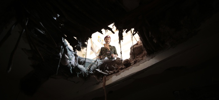 A soldier looks through a hole in a building damaged after an airstrike by Saudi-led coalition in Sanaa, Yemen, Tuesday, Sept. 20, 2016.