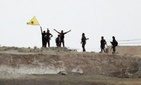 Kurdish fighters with the Kurdish People's Protection Units, or YPG, wave their yellow triangular flag in the outskirts of Tal Abyad, Syria, June 15, 2015.