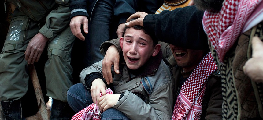 A Syrian child mourning at the funeral of his father