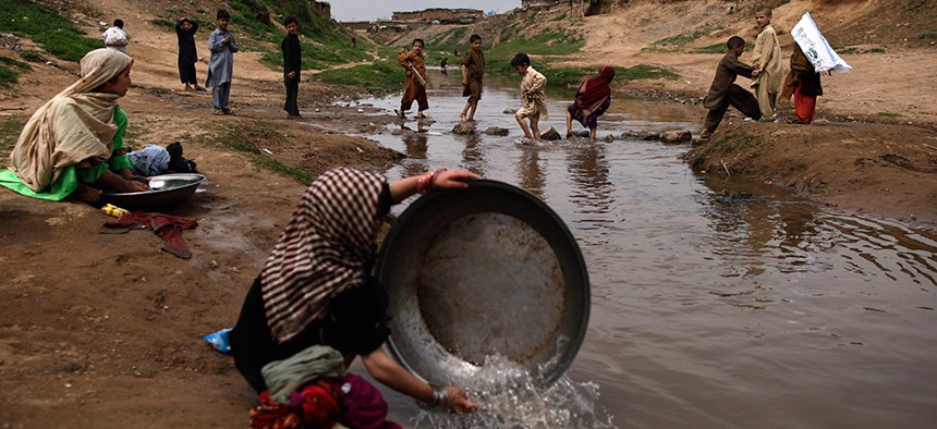 Girls in Pakistan washing their laundry near a polluted stream