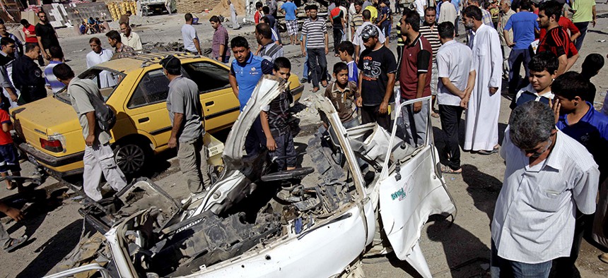 Iraqis walk around the aftermath of a car bomb attack in Sadr City, Baghdad