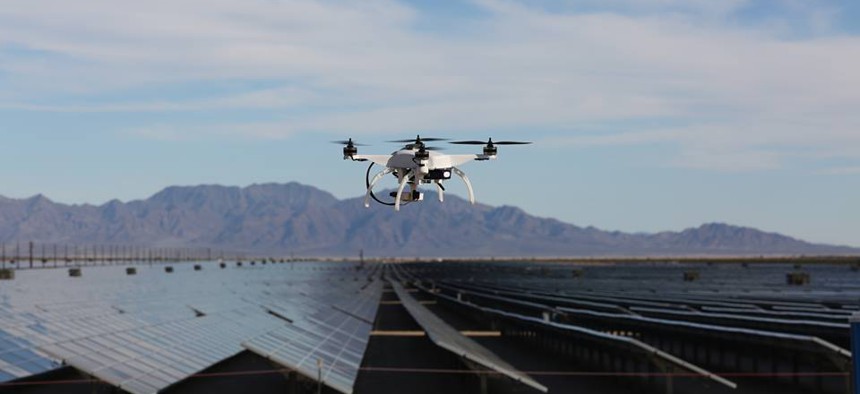 One of Skycatch's quadcopter drones hovers over a field of solar panels.
