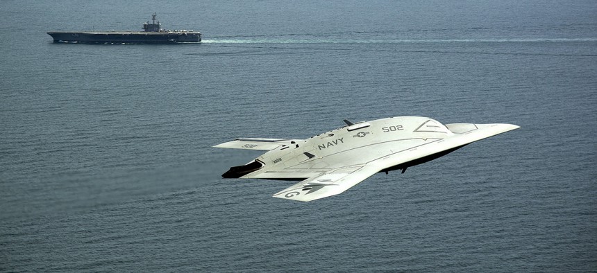 An X-47B drone, part of the Unmanned Combat Air System program, flies past the USS George H.W. Bush during a demonstration on May 14, 2013.