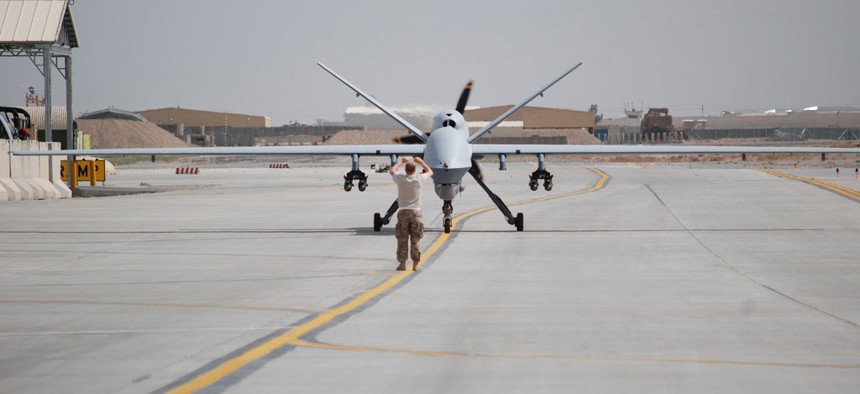 An airman with the 451st Air Expeditionary Group motions towards a MQ-9 Reaper drone taxiing at Kandahar Airfield, Afghanistan on March 20, 2014.