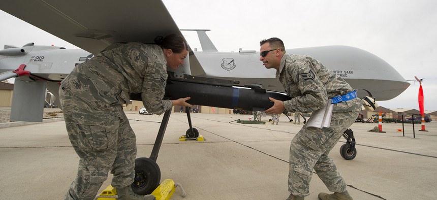 Two airmen load an inert missile onto an MQ-1 Predator drone during a competition at Holloman Air Force Base, N.M, on April 5, 2013.