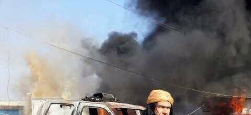 Shakir Waheib, a senior member of the al-Qaeda linked Islamic State of Iraq and the Levant, stands next to a burning police vehicle in Iraq's Anbar Province on January 4, 2014.