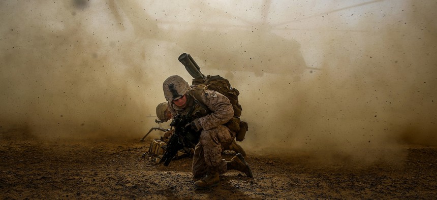 A Marine Corps corporal shields himself from dust kicked up by a CH-53E Super Sea Stallion lifting off during a mission in Helmand Province, Afghanistan, on April 28, 2014.