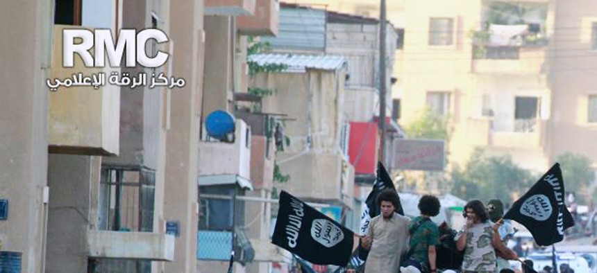 ISIL militants in Raqqa, Syria, wave flags during a military parade, on June 30, 2014.