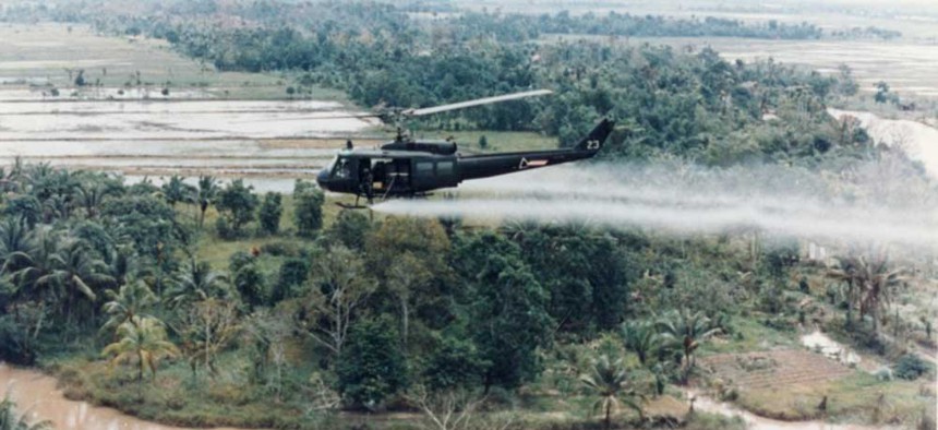 A U.S. Army Huey helicopter sprays Agent Orange over Vietnamese agricultural land. 