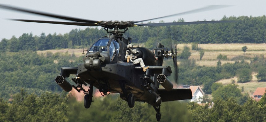 Two soldiers from the Multi-National Task Force ride on an Ah-64 Apache helicopter during an exercise at Camp Bondsteel, Kosovo. 