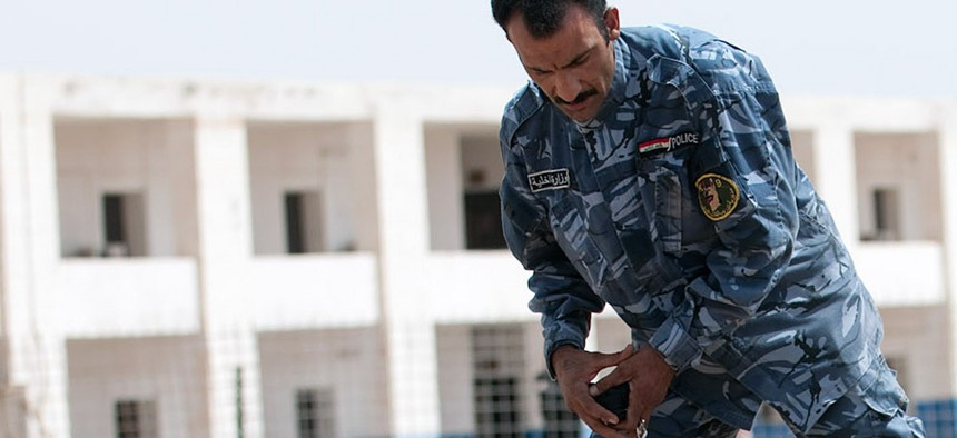 An Iraqi dog handler in Ramadi trains a German shepherd to find explosive samples. 