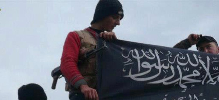 Militants with the Al-Qaeda affiliated Jabhat al-Nusra wave their flag on top of a Syrian air force helicopter at Taftanaz air base, in Idlib, Syria.