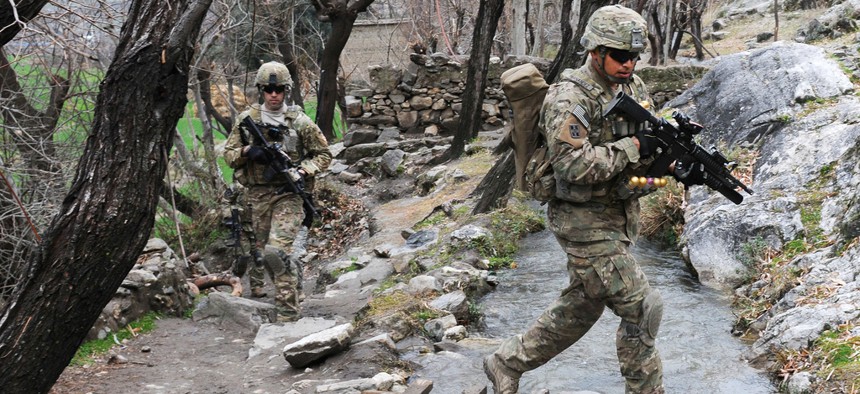 Two soldiers cross a stream during a unit visit to a village in Afghanistan's Kunar province. 