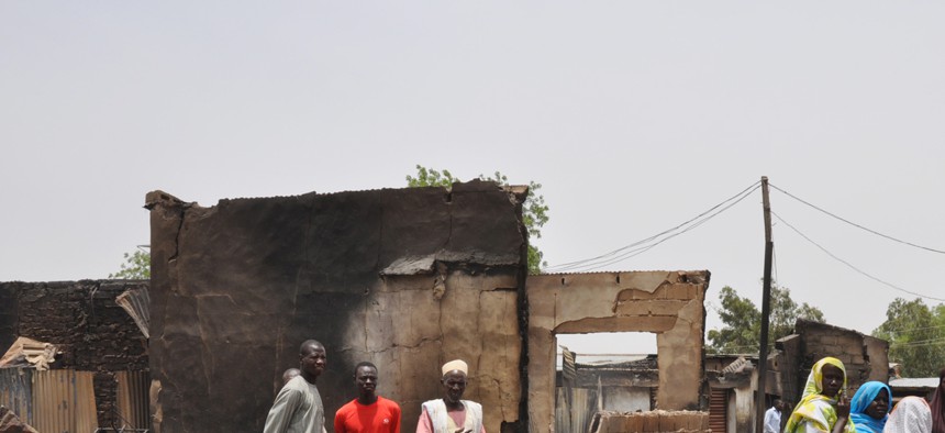 People stand outside burnt houses following an attack by militants in Gambaru, Nigeria, on May 11, 2014.