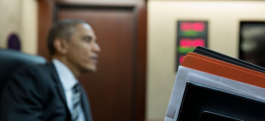 President Obama listens while Vice President Joe Biden holds his briefing book in the Situation Room, Nov. 25, 2014. 