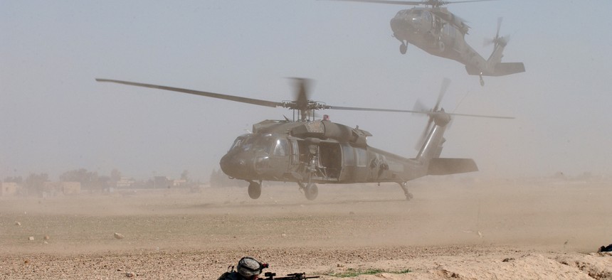 Two U.S. Army UH-60 Black Hawk helicopters blow up clouds of dust as they come into a landing zone in Samarra, Iraq.