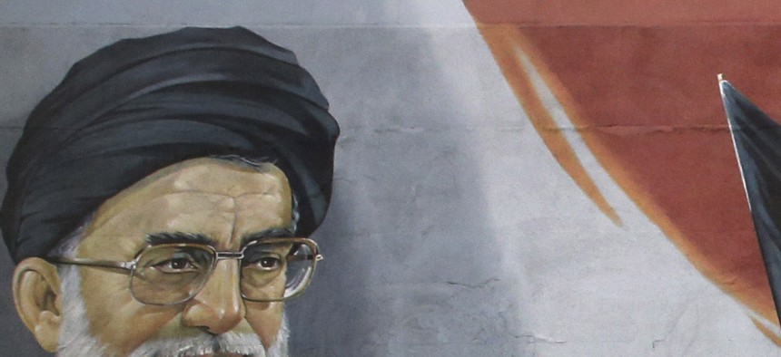 Pedestrians cross the Enqelab-e-Eslami (Islamic Revolution) street under a mural depicting famous Iran leaders and revolutionary fighters. 