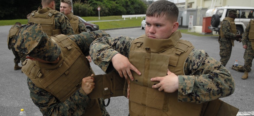 Marines with the 3rd Marine Logistics Group help each other configure their new Modular Tactical Vests before vest trainers inspect individual Marines for proper fit.