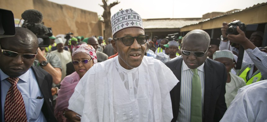 Opposition candidate Gen. Muhammadu Buhari, center, arrives to validate his voting card using a fingerprint reader, prior to casting his vote later in the day, in his home town of Daura, Nigeria Saturday, March 28, 2015. 