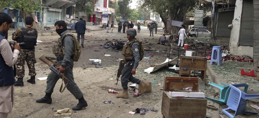Afghan security forces members inspect the site of a suicide attack near a new Kabul Bank in Jalalabad, east of Kabul, Afghanistan, Saturday, April, 18, 2015. 