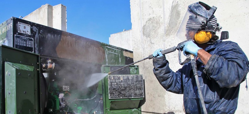 A private contractor sprays water to clean parts of a generator at Forward Operating Base Shank, Logar province, Afghanistan, March 14, 2012.