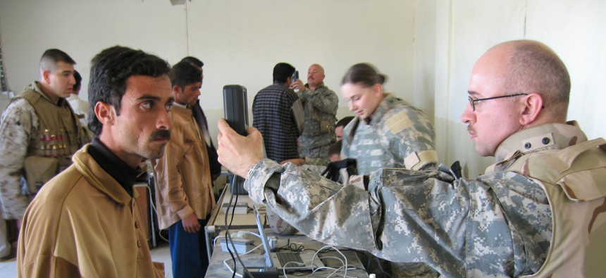 An unidentified U.S. soldier conducts an iris scan on an Iraqi man during an Iraqi army recruiting drive in the city of Ramadi on Monday March 27, 2006.