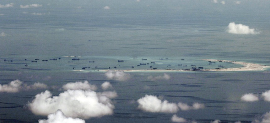 This aerial photo taken through a glass window of a military plane shows China's alleged on-going reclamation of Mischief Reef in the Spratly Islands in the South China Sea Monday, May 11, 2015.