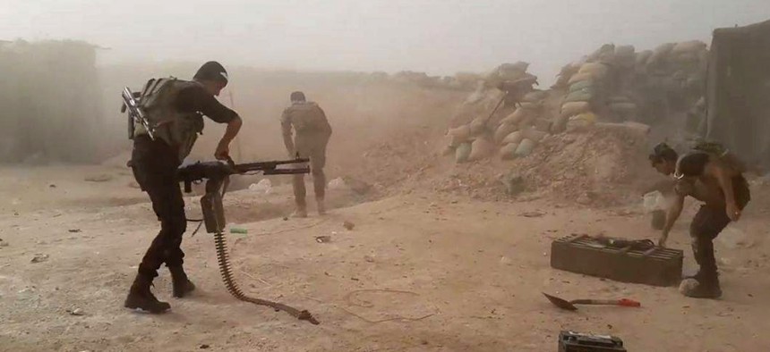 In this image taken Friday, May 29, 2015, Iraqi anti-terrorism forces battle with Islamic State group extremists as they defend their base against Islamic State group extremist attack outside Fallujah.