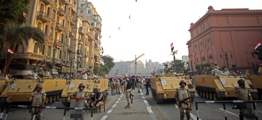 Egyptian military helicopters fly overhead as army soldiers stand guard at an entrance to Tahrir Square, in Cairo, Egypt., on October 6, 2013.