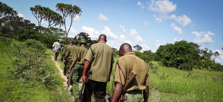 Armed members of the Kenyan security forces march in single file along narrow paths leading through the dense swamp and forest, searching for attackers about 60 miles from the Somali border on the coast of Kenya, June 17, 2014.