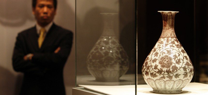 Pilfering data isn't like stealing this vase. A security man stands guard next to a early Ming underglaze copper-red vase during an auction by Christie's in Hong Kong Tuesday, May 30, 2006. 