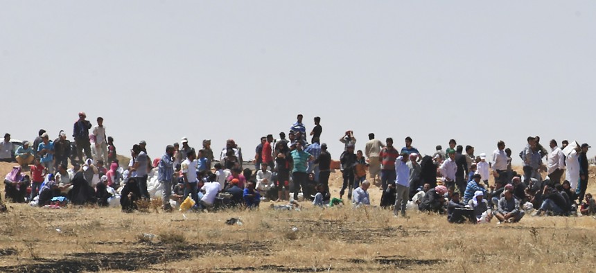 Syrian refugees wait on the Syrian side of the Syria-Turkey border in order to cross, Thursday, June 11, 2015.