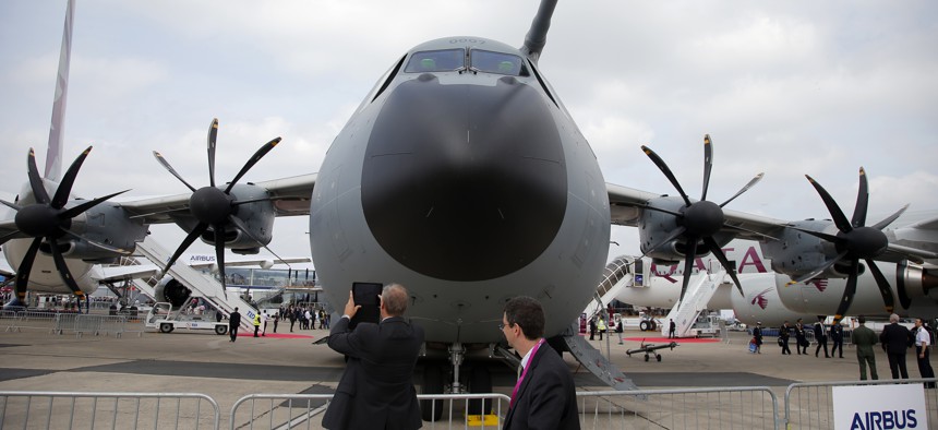 Visitors look at the Airbus A400M military transport aircraft presented at the Paris Air Show, at Le Bourget airport, north of Paris, Monday, June 15, 2015.