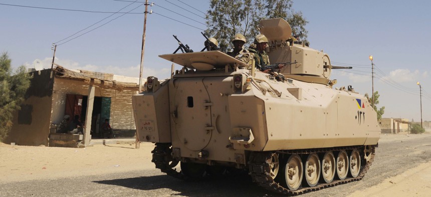Egyptian Army soldiers patrol in an armored vehicle backed by a helicopter gunship during a sweep through villages in Sheikh Zuweyid, north Sinai, Egypt, on May 12, 2013.