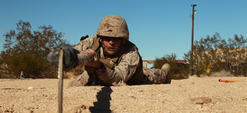 An enlisted Marine employs a bamboo sickle stick to search for buried improvised explosive devices at the Combat Center's Range 800 Feb. 13, 2013.