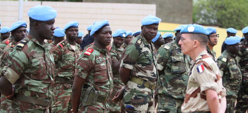 A French soldier stands alongside African troops who helped France take back Mali's north earlier this year, as they participate in a ceremony formally transforming the force into a United Nations peacekeeping mission, in Bamako, Mali, July 1, 2013.